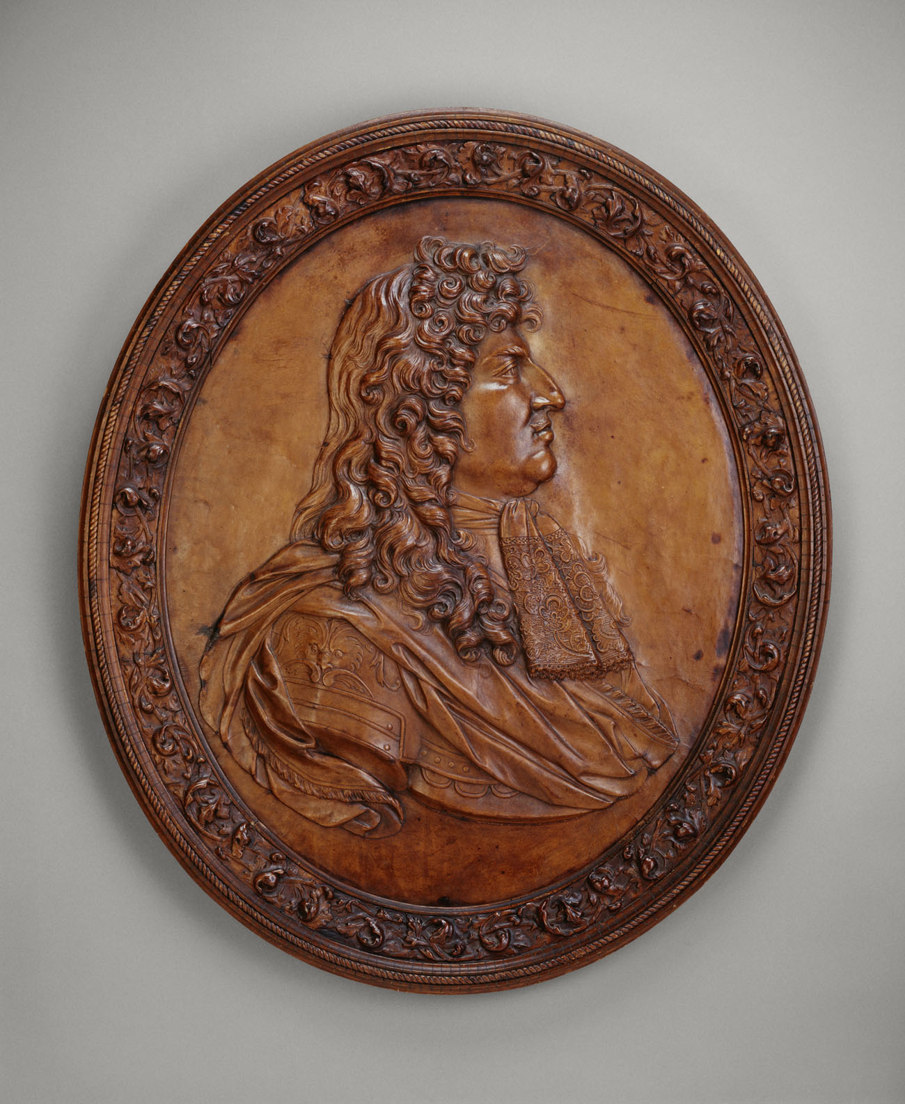 An oval sculpted leather portrait of Louis XIV looking to the right