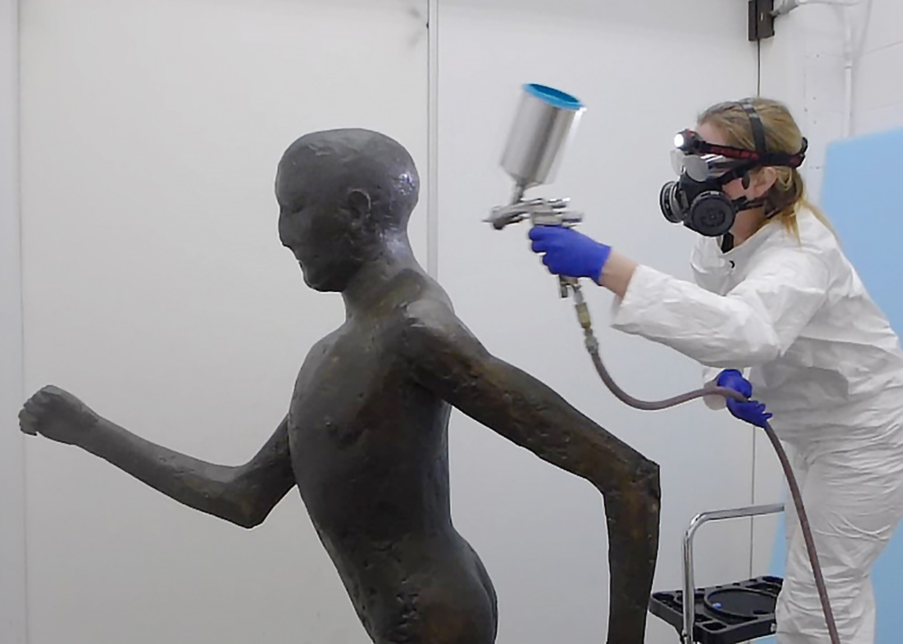 Conservator Julie Wolfe adds protective coatings to a sculpture.
