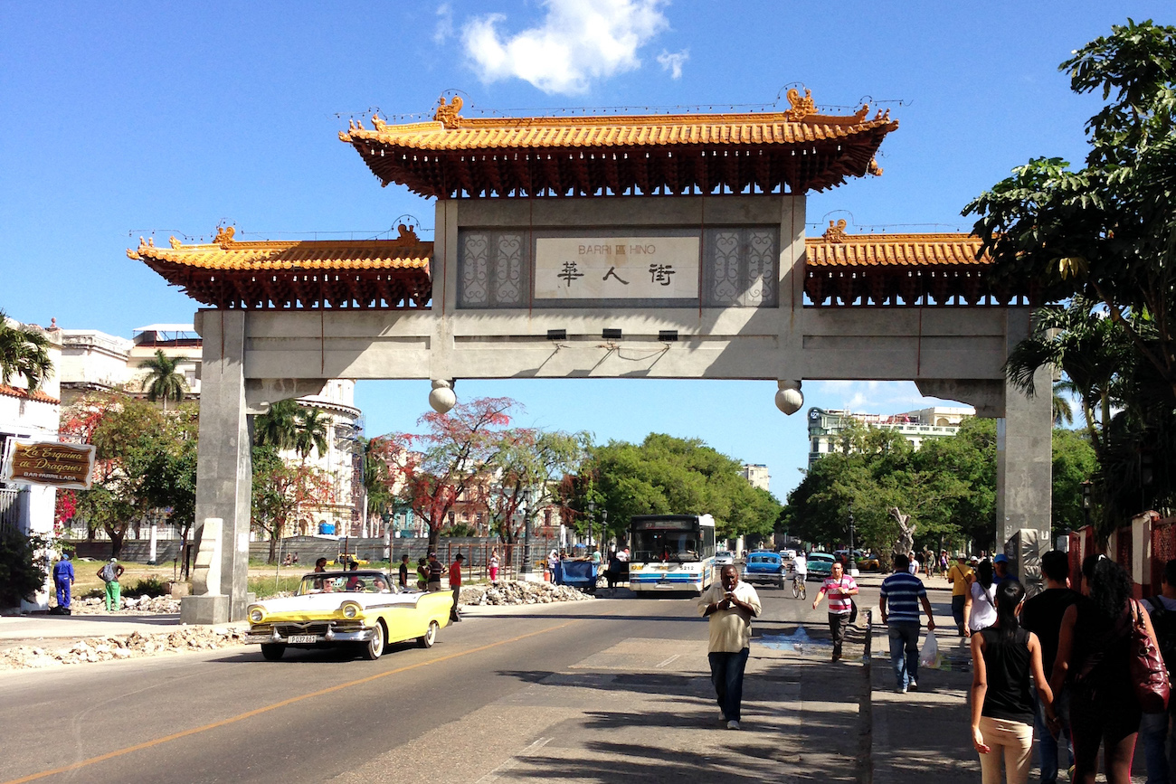 Color photo of a Chinese-style concrete gate spanning a two-lane public street in Havana