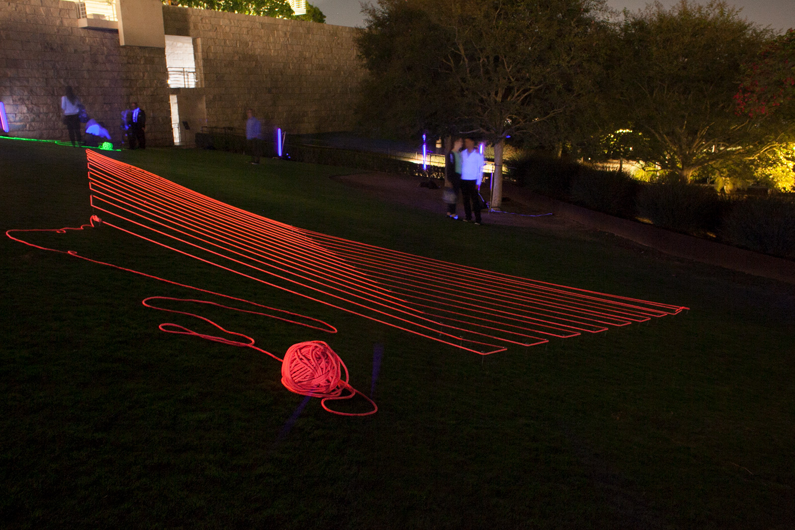 Nighttime view of a large lawn with bright pink glowing rope arrayed in parallel lines