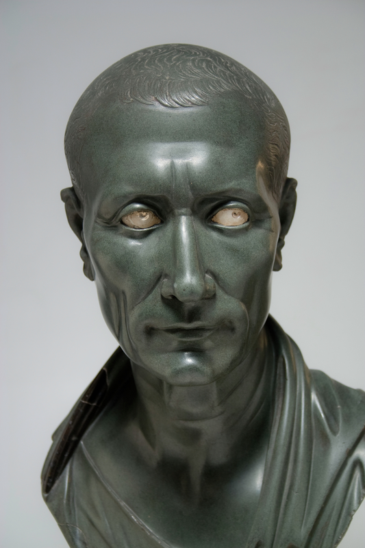 green sculpture of bust of man with inset white eyes.