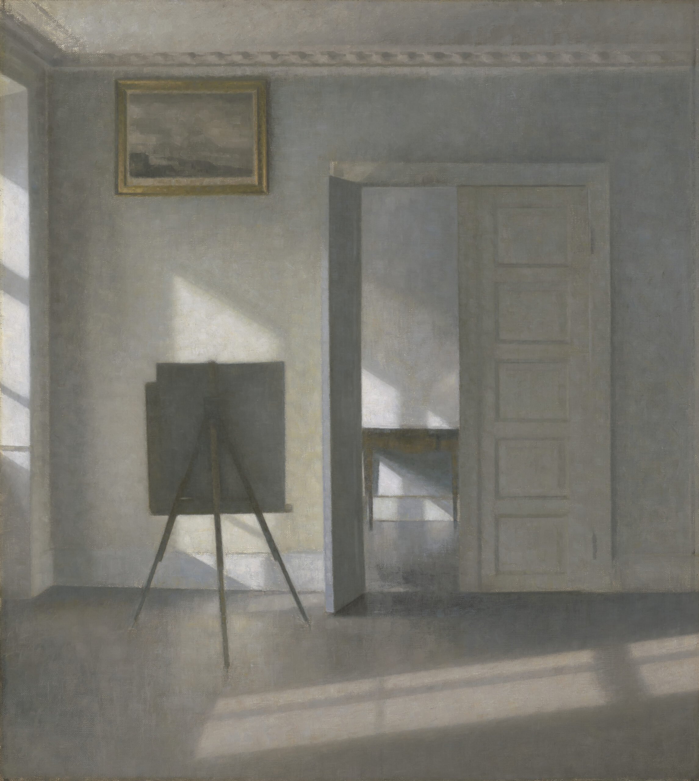 Painting of a room in muted tones shows an easel on the left with a painting high on the wall above it. There is a window to the left that casts shadows across the room.