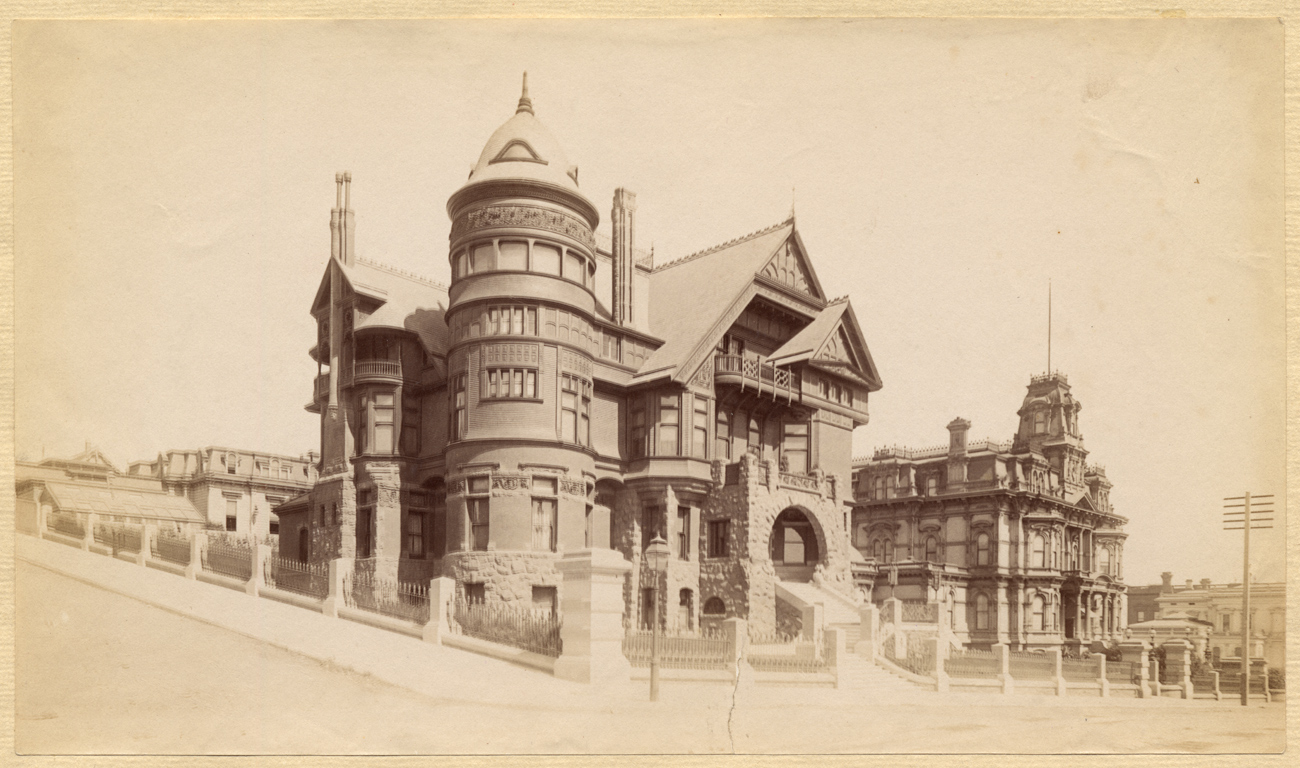 Sepia photo of a large house with gables and turrets, with nothing else nearby