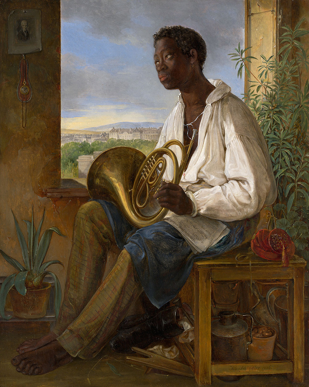 A dark-skinned man (or boy) sits by a window. He's wearing a white shirt and holding a French horn.