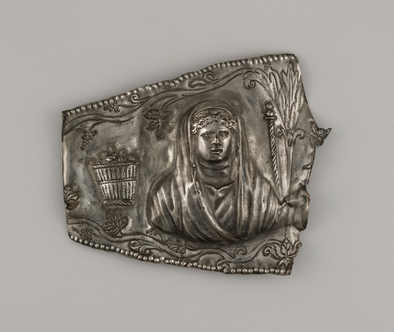 A silver piece with the image of a woman.