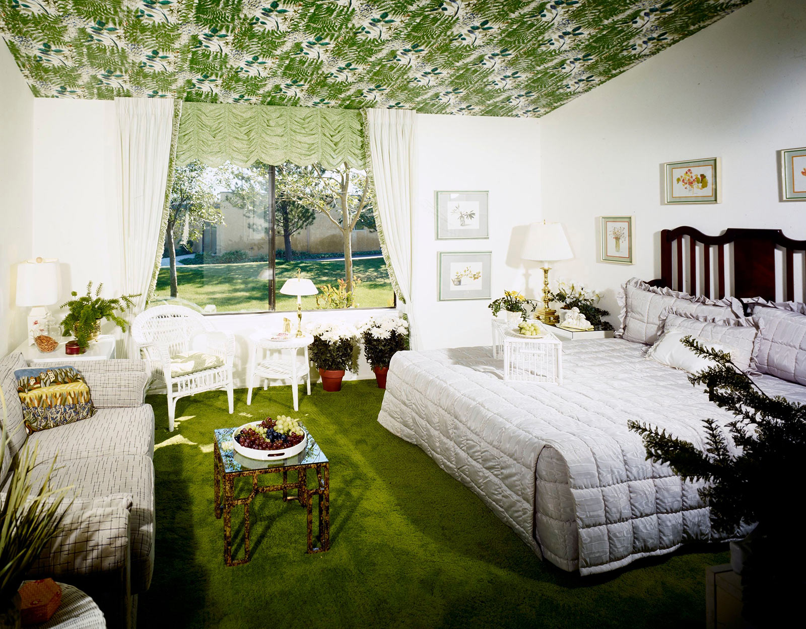 Bedroom with white and gray linens and accents, grass green carpet, and green leaf patterned ceiling