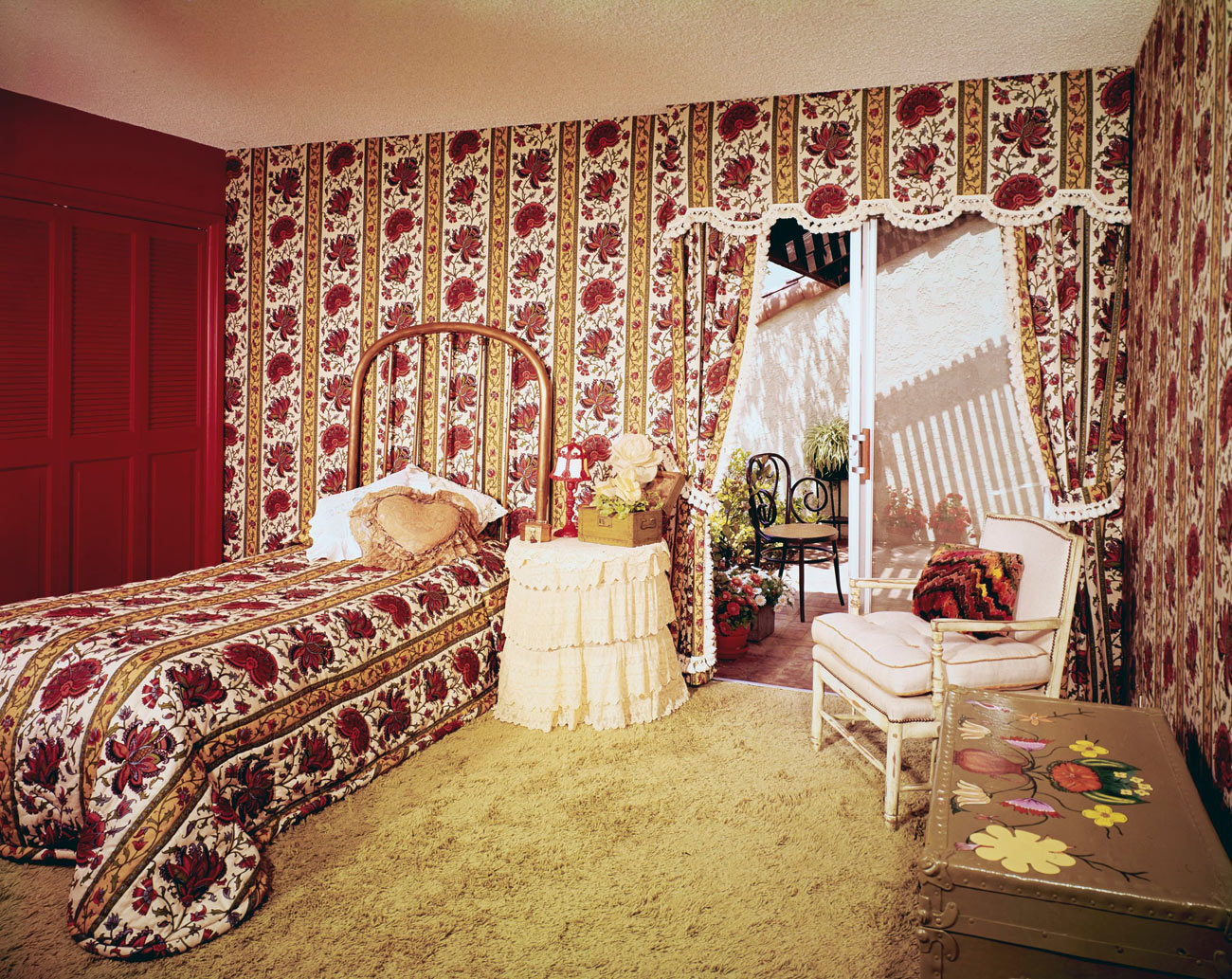 Bedroom with floral and stripe patterned wallpaper and matching bedspread on the twin bed.