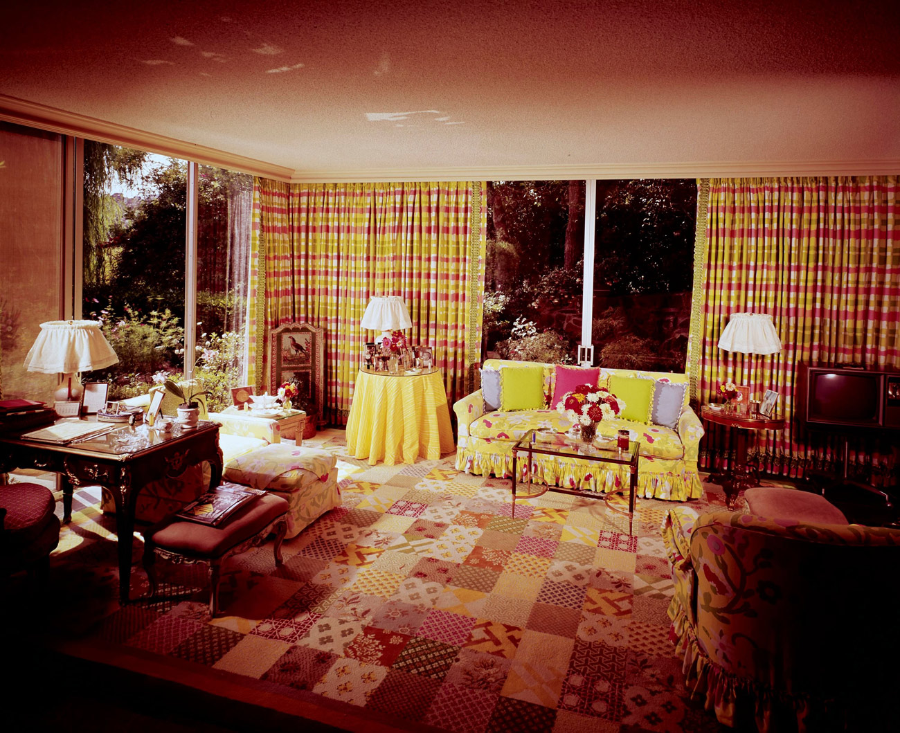 Living room with yellow and red accents. The carpet looks like a patchwork quilt.