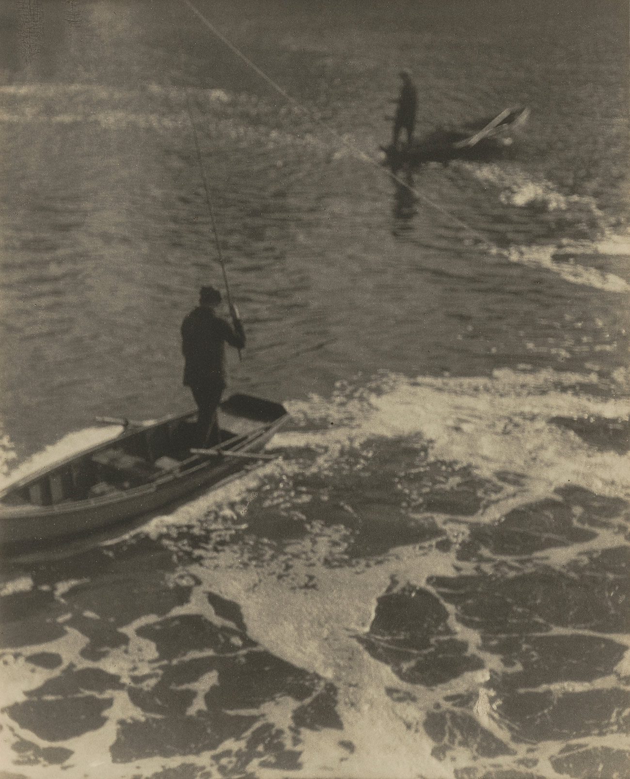 Photo from above of two people fishing while standing in the stern of their respective rowboats.