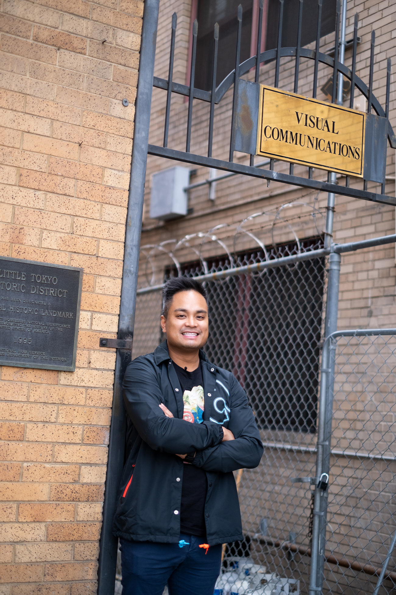 Young man standing next to a brick wall with a sign that says Little Tokyo Historic District