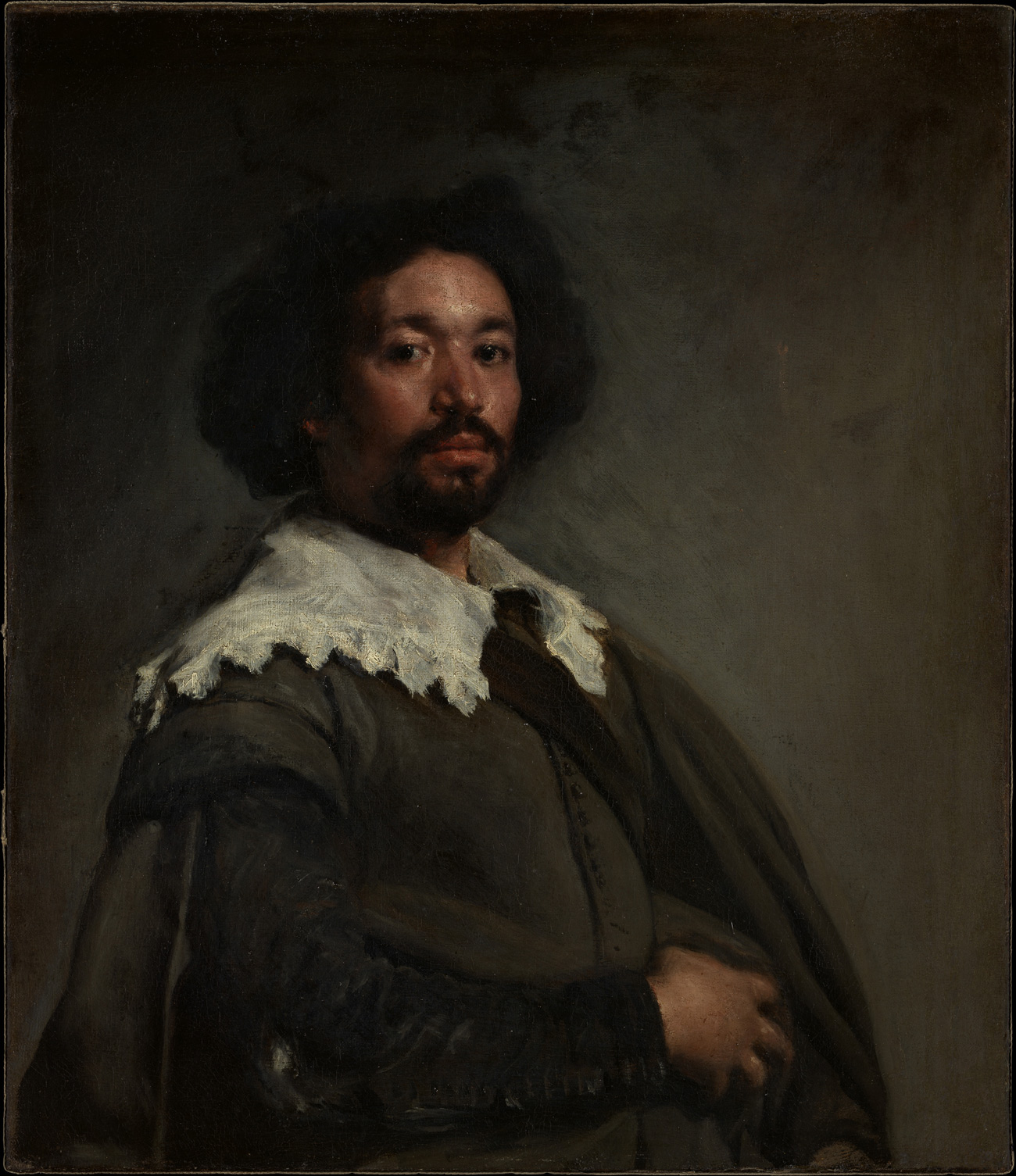 Man wearing a black robe with white collar sits for a portrait