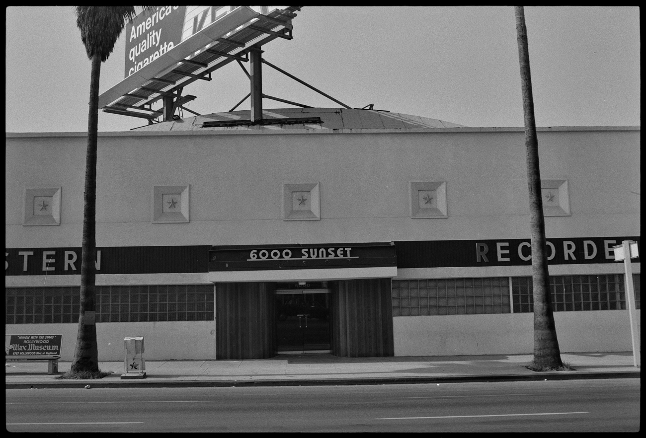Street view of a two-story building with art moderne style square decorative motif on the outside of the building and lettering that says Western Recorders and the address, 6000 Sunset