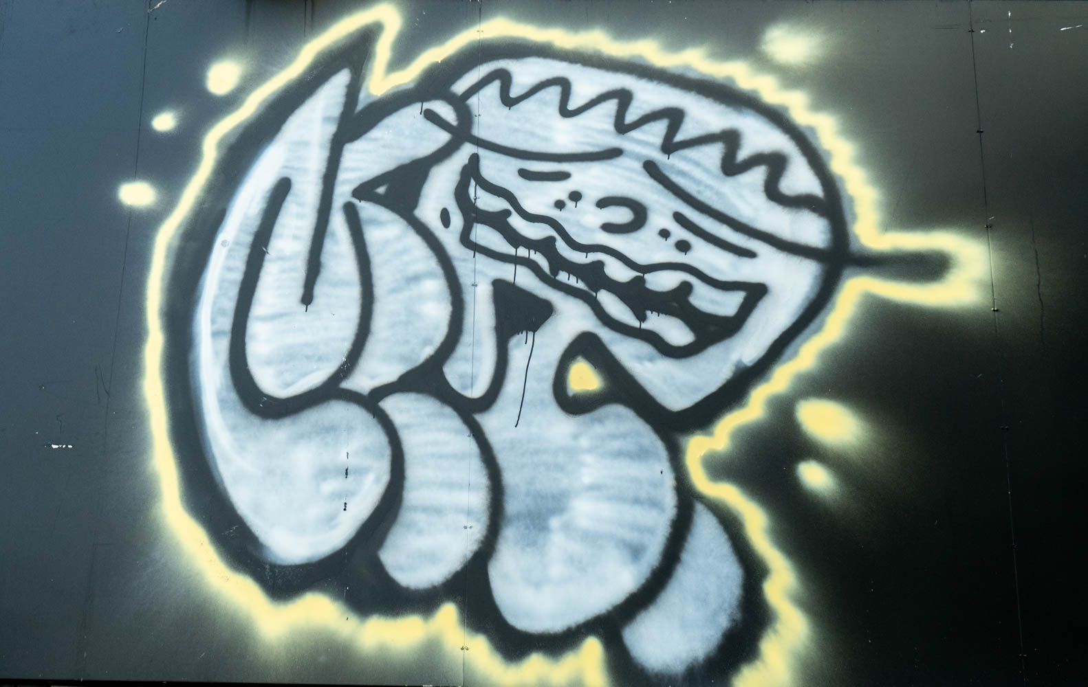 Graffiti artwork of an anguished face in gray, outlined in black and yellow