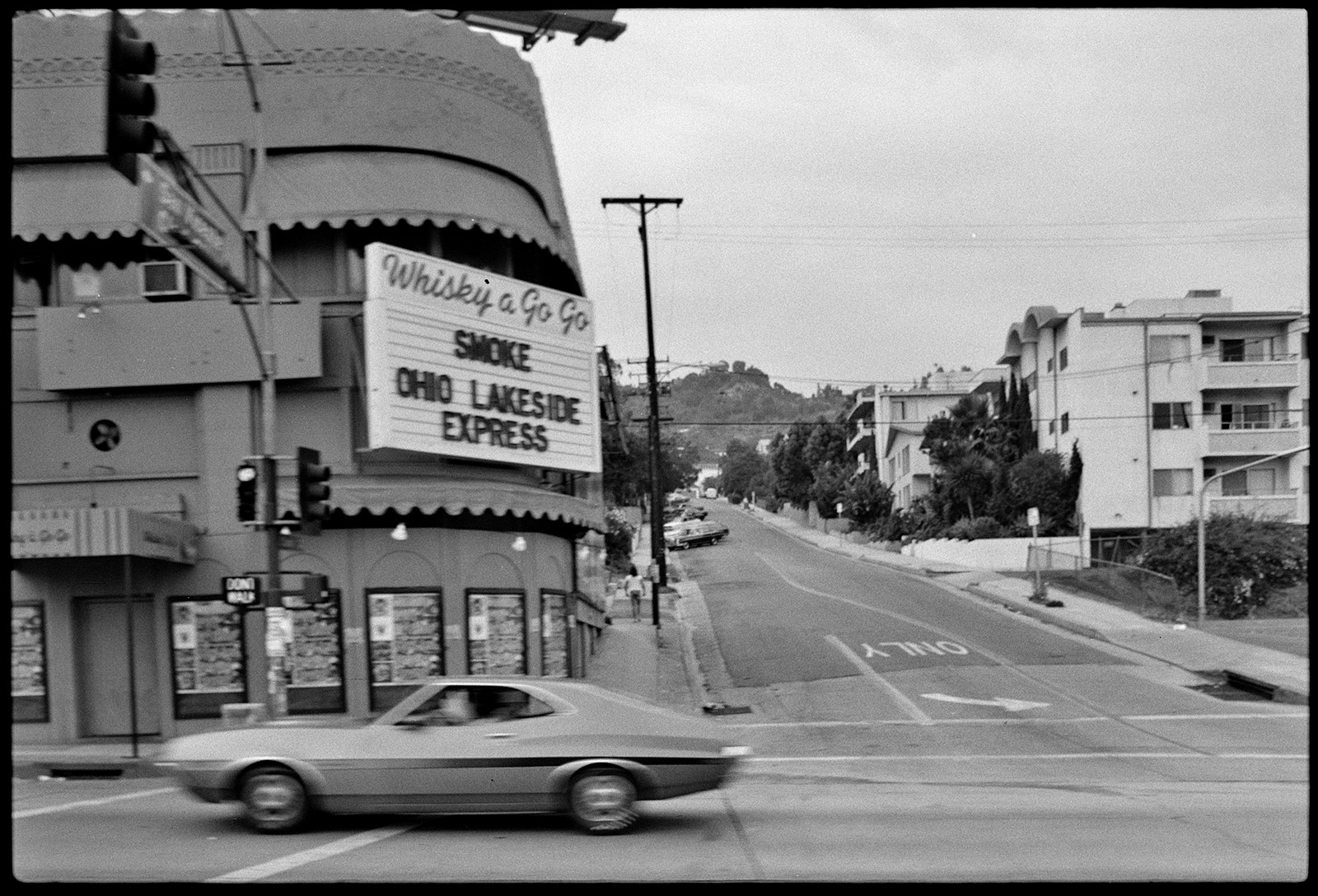 Building with a marquee in the front that says Whisky a Go Go, Smoke, Ohio Lakeside Express; the building is at the corner of the street and across the street are large apartment buildings