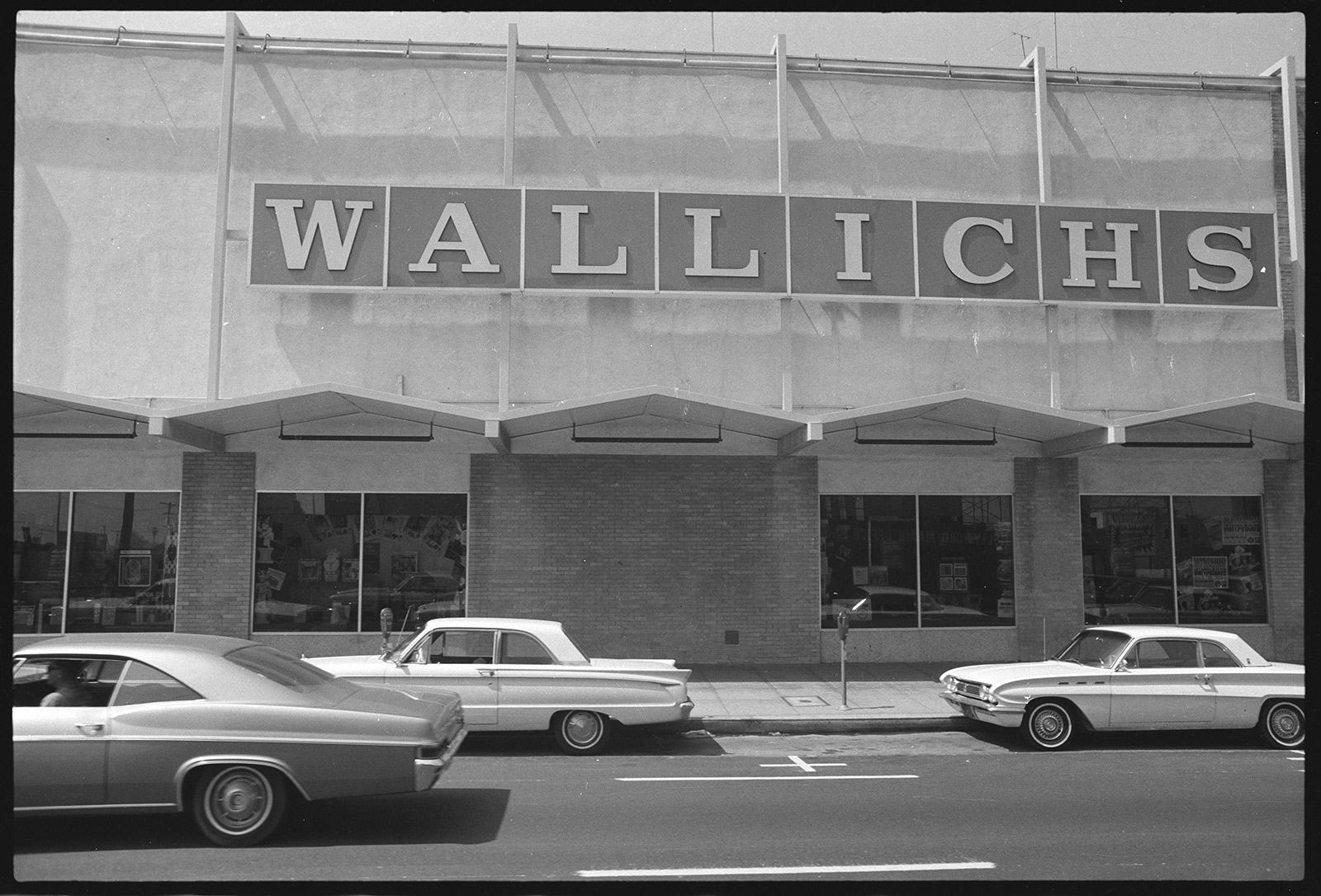 Front of store with a row of windows at the ground level and large lettering above that says Wallichs