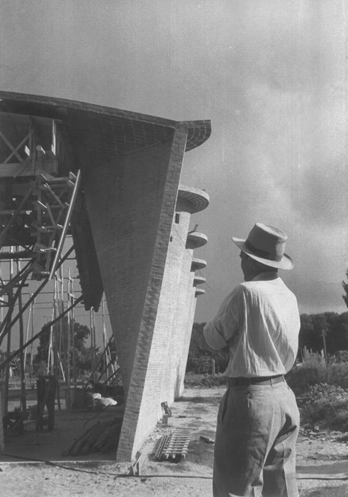 Black and white photograph of the Cristo Obrero church under construction, as the architect looks at it with his back to the camera