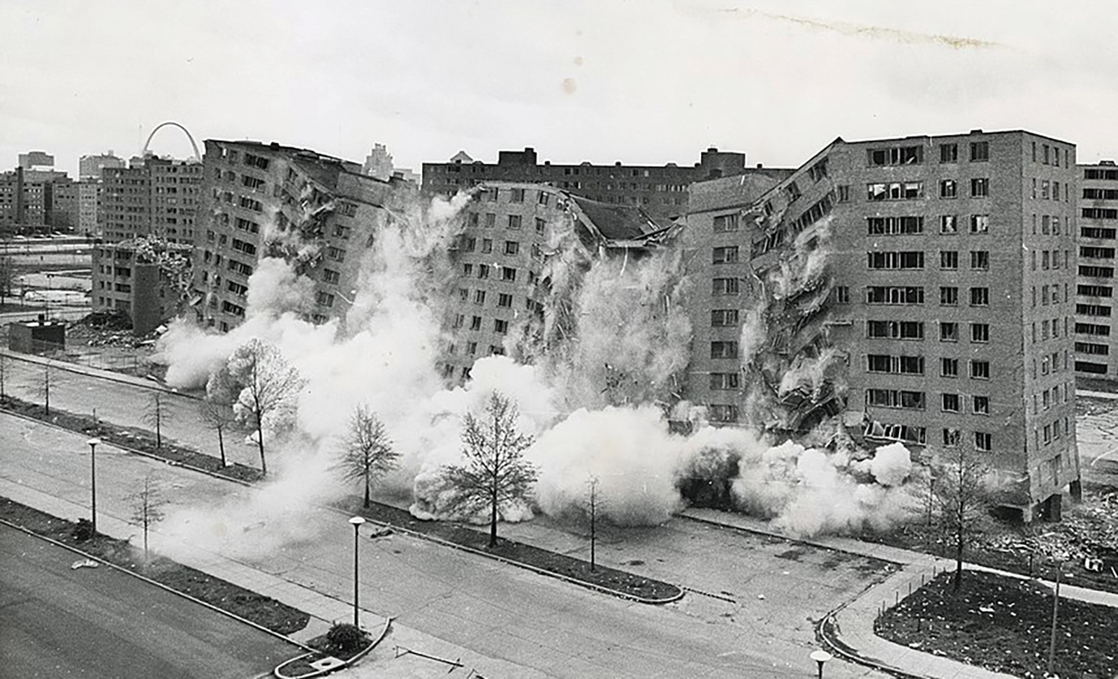 Tall buildings photographed in the midst of demolition, surrounded by billowing smoke.
