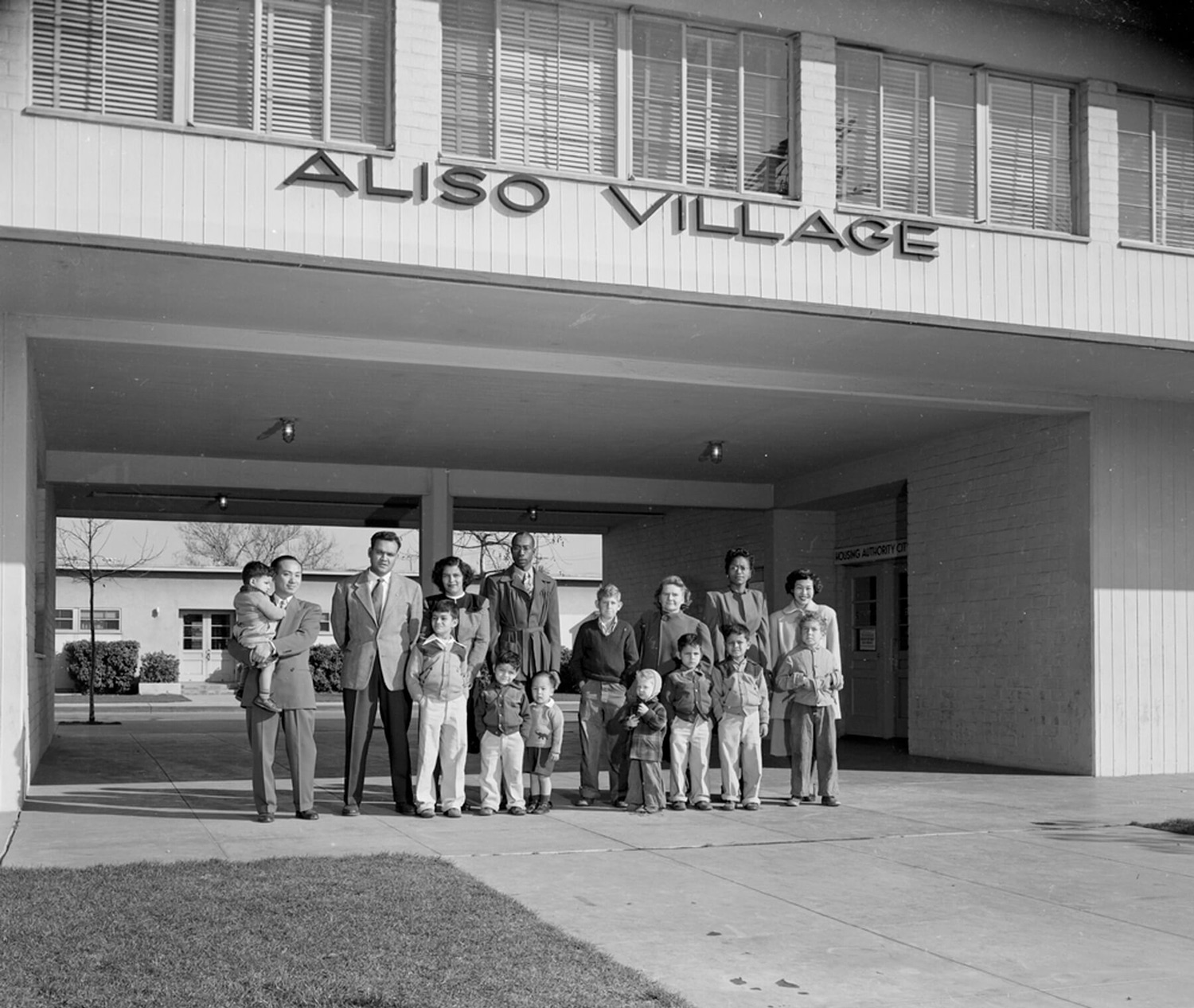 Families pose in front of the Aliso Village apartment complex.