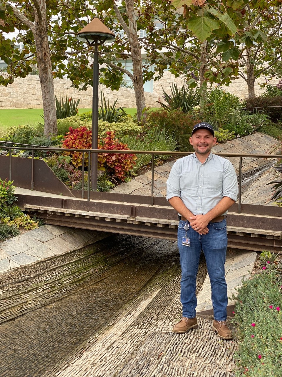 A man stands along the water feature that runs through the Getty's Irwin garden